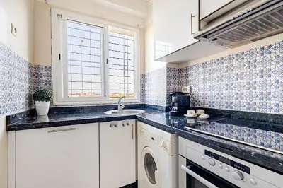 a kitchen with white cabinets and blue tiles at Comfort Pool Apartment Heart of Tamaris in Tamaris