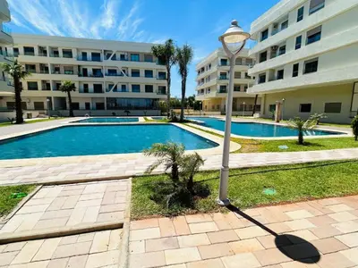 a light pole in front of a building with a swimming pool at Appartement neuf avec piscine, balcon et à deux pas de la mer