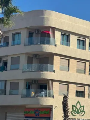 an apartment building with a balcony with a red umbrella at Appartement neuf avec piscine, balcon et à deux pas de la mer