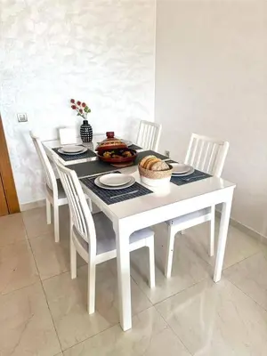 a white table with chairs and a bowl of food on it at Appartement neuf avec piscine, balcon et à deux pas de la mer