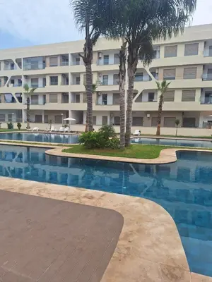 a hotel with a swimming pool in front of a building at Appartement neuf avec piscine, balcon et à deux pas de la mer