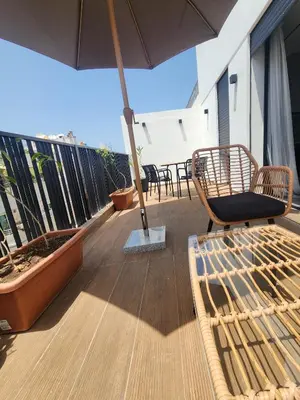 a balcony with chairs and an umbrella on a roof at The 28 Triangle d'Or by IB Signature - Stylish two-Bedroom flat - Wifi, Self Check-in, Day and Night Security, Terrace, Swimming pool, free parking close to all amenities in Casablanca