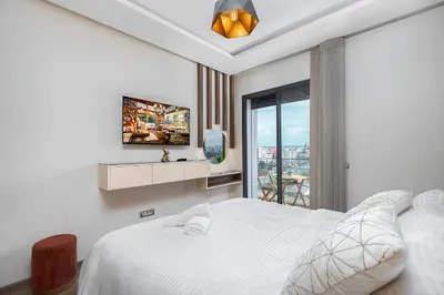 a white bedroom with a bed and a balcony at Luxury Apartment Perles d'Agdal, Facing Agdal Station in Rabat