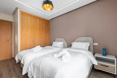 two beds in a room with white sheets and towels at Luxury Apartment Perles d'Agdal, Facing Agdal Station in Rabat