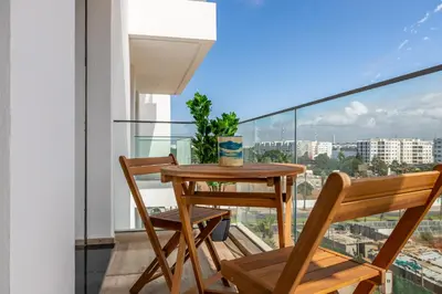 a balcony with a wooden table and two chairs at Luxury Apartment Perles d'Agdal, Facing Agdal Station in Rabat