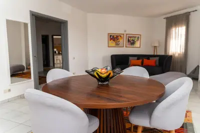 a dining room with a wooden table and white chairs at Spacious and colorful apartment close to MahajRiad in Rabat