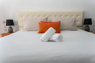 a white bed with orange and white pillows on it at Spacious and colorful apartment close to MahajRiad in Rabat