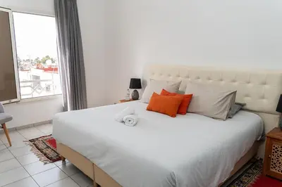 a bedroom with a large white bed with orange pillows at Spacious and colorful apartment close to MahajRiad in Rabat