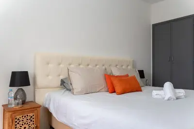 a bedroom with a large white bed with orange pillows at Spacious and colorful apartment close to MahajRiad in Rabat