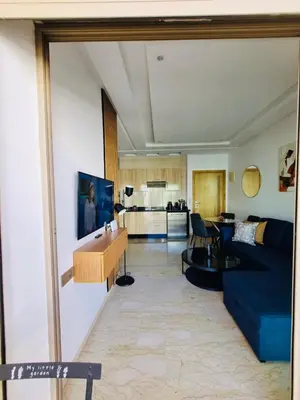 a living room with a blue couch and a kitchen at BenHost Appartement Casablanca Maarif in Casablanca