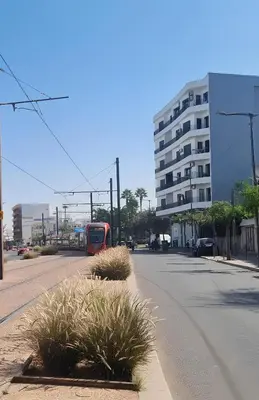 a red bus driving down a street with a building at BenHost Appartement Casablanca Maarif in Casablanca