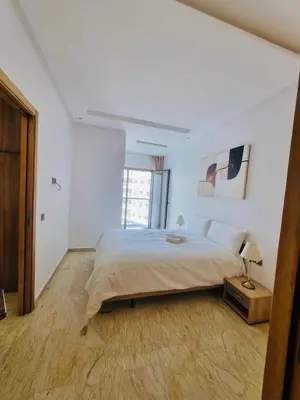 a white bedroom with a large bed and a table at BenHost Appartement Casablanca Maarif in Casablanca