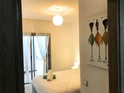 a bedroom with a bed and a room with a mirror at Apartment with large terrace Mohammedia in Mohammedia