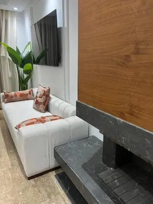 a living room with a white couch and a fireplace at Apartement avec piscine privée Casablanca in Casablanca