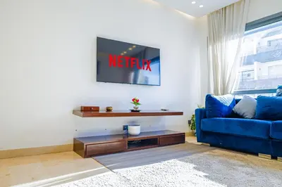 a living room with a blue couch and a tv at VIVASTAY Casablanca - Urban Nest 3 Bedrooms High Standing Les Princesses in Casablanca