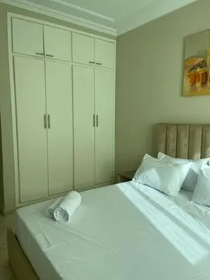 a bedroom with a white bed with white cabinets at Appartement calme et lumineux à Harhoura in El Harhoura