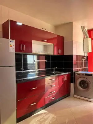 a kitchen with red cabinets and a washing machine at Appartement calme et lumineux à Harhoura in El Harhoura