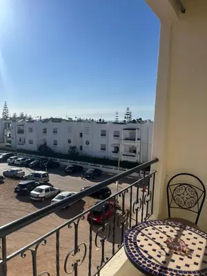 a balcony with a table and a view of a parking lot at Appartement calme et lumineux à Harhoura in El Harhoura