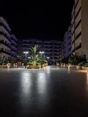 a parking lot at night with buildings and palm trees at Apartment in Manesman beach in Mohammedia