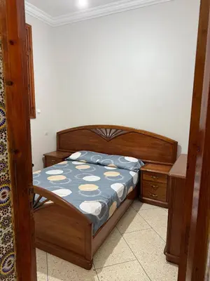 a bedroom with a bed and a wooden bed frame at Beautiful apartment with all comforts in Rabat