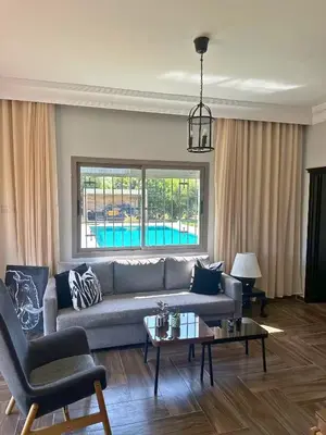 a living room with a couch and a table at Ferme moderne avec piscine et jardin Sejour paisible au cœur de la nature in Berrechid