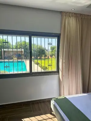 a bedroom with a large window with a view of a pool at Ferme moderne avec piscine et jardin Sejour paisible au cœur de la nature in Berrechid