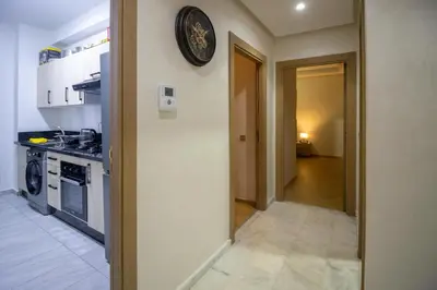 a kitchen with a clock on the wall and a hallway at Beautiful apartment with pool view in Aïn Harrouda