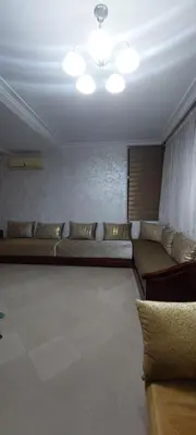 a living room with a long couch and a ceiling at apparttement confort residence marina beach a mohammedia in Mohammedia