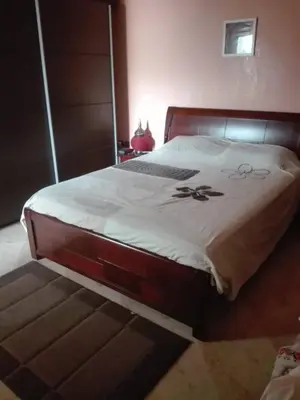 a large bed in a bedroom with a wooden frame at apparttement confort residence marina beach a mohammedia in Mohammedia