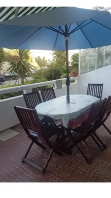a table with a blue umbrella and two chairs at appartement a la residence marina beach a mohammedia plage in Mohammedia