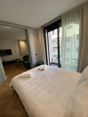 a bedroom with a large white bed and a living room at Cosy & Modern apartment with balcony, fiber WiFi & air conditioning Close To KFC & Mcdo Bd 2 Mars In The Heart Of Casablanca in Casablanca
