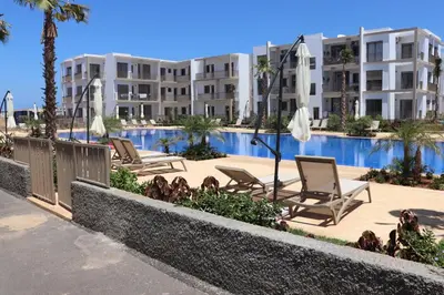 a row of lounge chairs next to a swimming pool at Appartement neuf meublé avec piscine in Mansouria