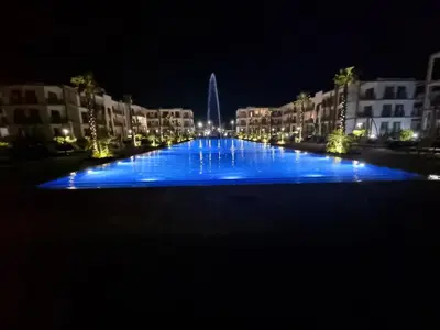 a large pool with blue lights at night at Appartement neuf meublé avec piscine in Mansouria