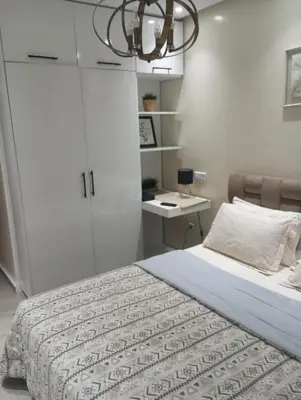 a bedroom with a bed and a desk and a chandelier at Apartment at Melissa's, sea view, Res Assabah in Rabat