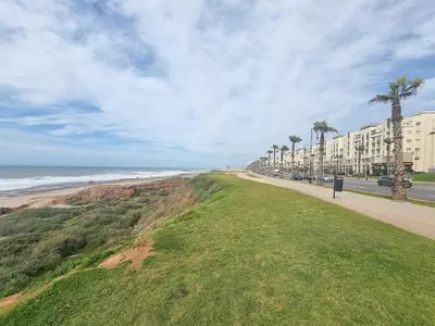a road next to a beach with palm trees and buildings at Blue paradise in Rabat