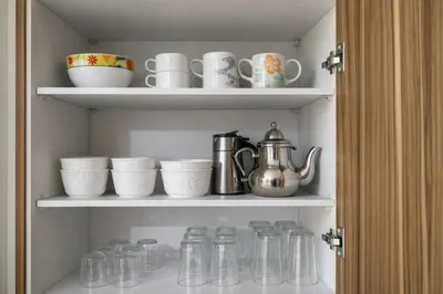 a cupboard filled with glass jars and cups at Walkable, Beach in 2, Terrace, DW, AC, PS4, WiFi in Mohammedia