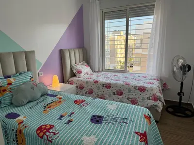 a childs bedroom with two beds and a window at Blue Ocean Escape Sidi Rhal in Sidi Rahal