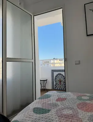 a bedroom with a bed and a view of a balcony at Blue Ocean Escape Sidi Rhal in Sidi Rahal