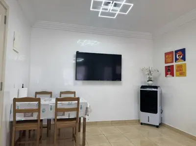 a dining room with a table and a tv on a wall at Blue Ocean Escape Sidi Rhal in Sidi Rahal