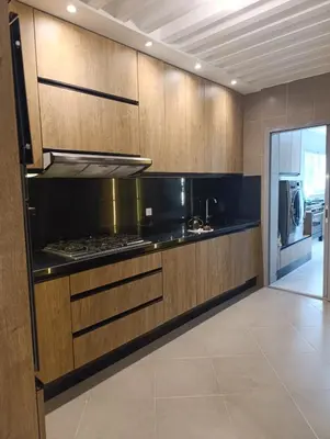 a kitchen with wooden cabinets and a stove top oven at Hamza in Temara