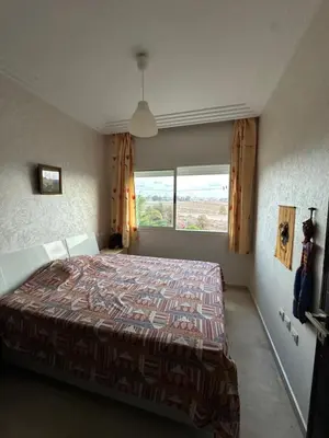 a bedroom with a bed and a large window at Appartement Cosy Bord de Mer in Dar Mohammed Ould Haj Jilali