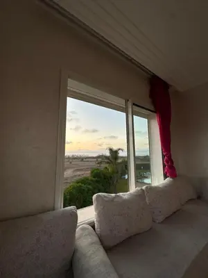 a living room with a couch and a large window at Appartement Cosy Bord de Mer in Dar Mohammed Ould Haj Jilali
