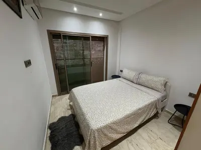 a white bedroom with a bed and a window at Cosy Studio meublé in Casablanca