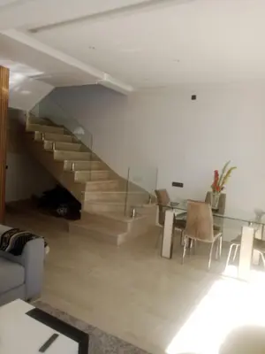 a living room with a staircase and a table and chairs at Duplex moderne avec jardin privé 5 min de la mer in Skhirat