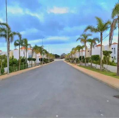 an empty street with palm trees and houses at Duplex moderne avec jardin privé 5 min de la mer in Skhirat