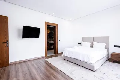 a white bedroom with a bed and a flat screen tv at Villa Indigo in Rabat