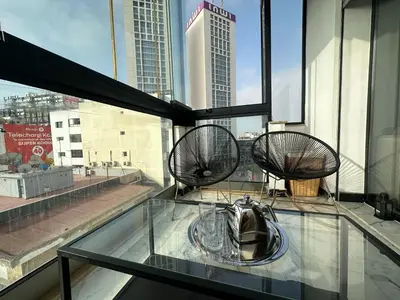 a glass table with two chairs on top of a building at Luxury Modern Apartment in the Heart of the City with Balcony Overlooking Twin Towers in Casablanca