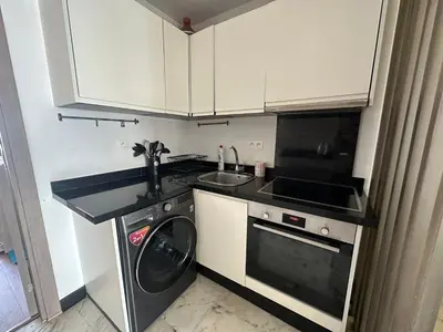 a small kitchen with a sink and a washing machine at Luxury Modern Apartment in the Heart of the City with Balcony Overlooking Twin Towers in Casablanca