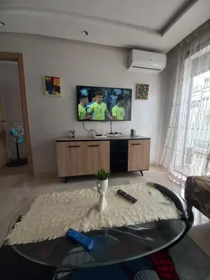a living room with a tv and a glass table at La perle home 21 in Casablanca-Port