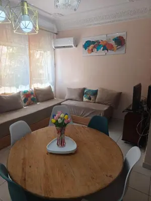 a living room with a wooden table with a vase of flowers at Baraka house in Sidi Yahia az Zaʼer